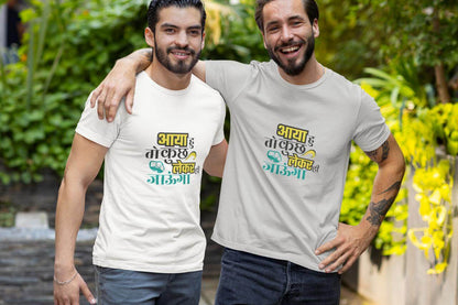 Two men wearing vibrant "ABHI MAZA AAYEGA NA BHIDU" unisex T-shirts, smiling outdoors in comfortable and stylish round-neck shirts.