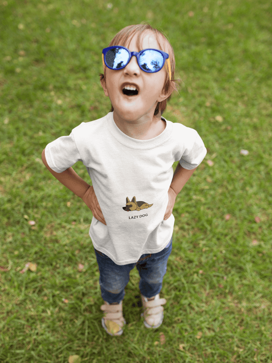 Child wearing Lazy Dog Kids T-Shirt, super combed bio-washed fabric with double stitched seams, ribbed neck, and blue sunglasses, standing on grass.