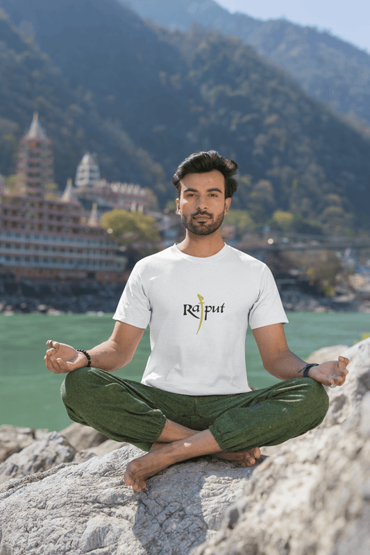 Man meditating in Rajput Round Neck Tshirt in a serene mountain and river setting.