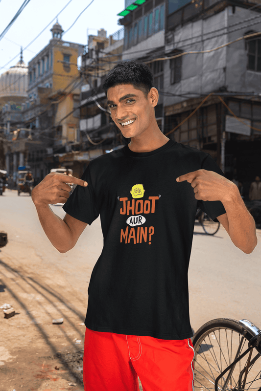 Smiling person wearing black unisex "Jhooth Aur Main?" Tshirt with vibrant colors, posing confidently on a street.