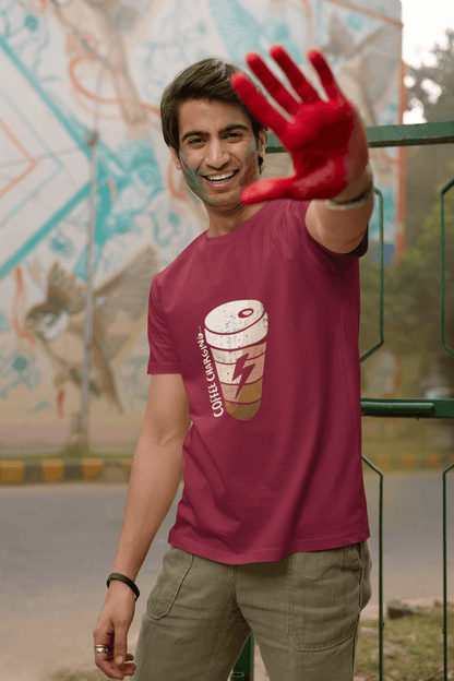 Person wearing Coffee Charging Round Neck unisex T-shirt in vibrant color, posing with hand raised.
