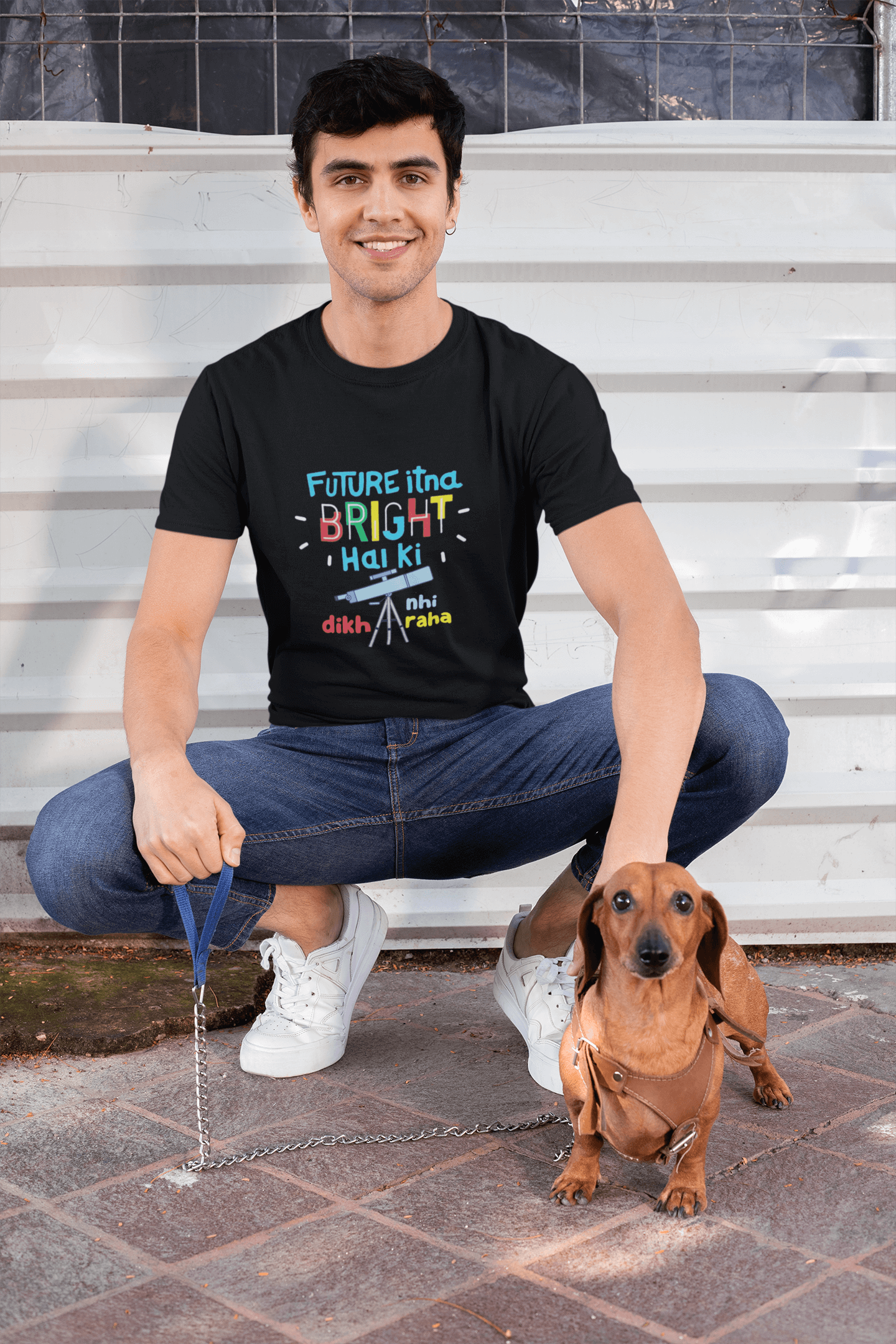 Man wearing a funky round neck t-shirt with a colorful design, sitting with a small dog, showcasing Future Bright tee in vibrant colors.