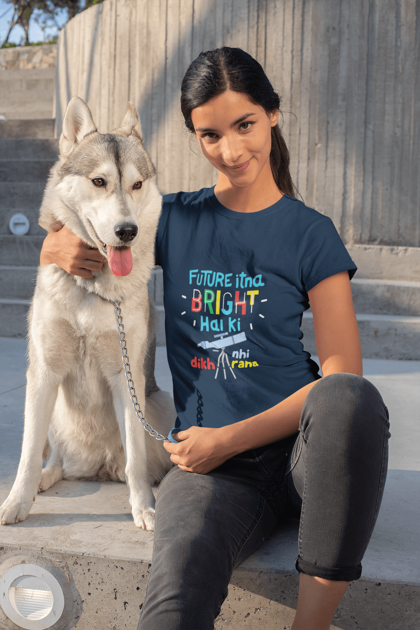 Woman wearing a blue "Future Bright" funky T-shirt, sitting with a Husky dog on a sunny day.